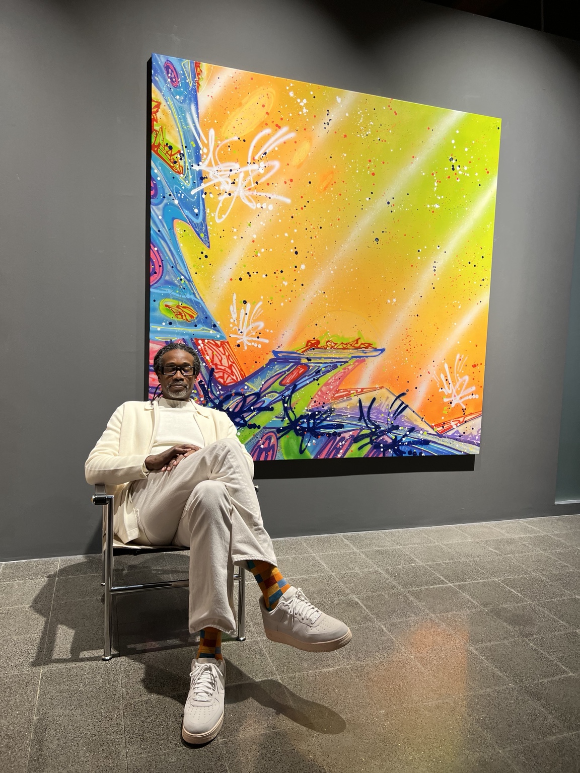 Kool Koor seated in front of a painting
